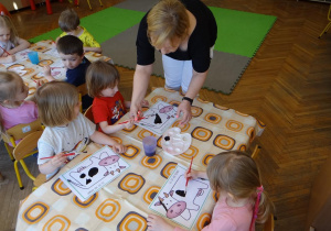 Nauczycielka pomaga dzieciom w malowaniu